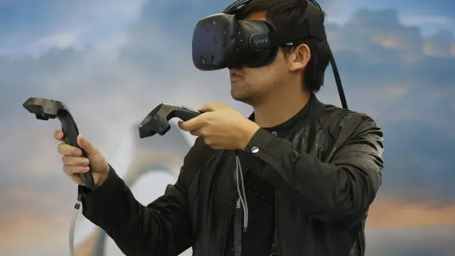 Un visitante usa unas gafas de realidad virtual para jugar a los videojuegos en un salón en Pekín.