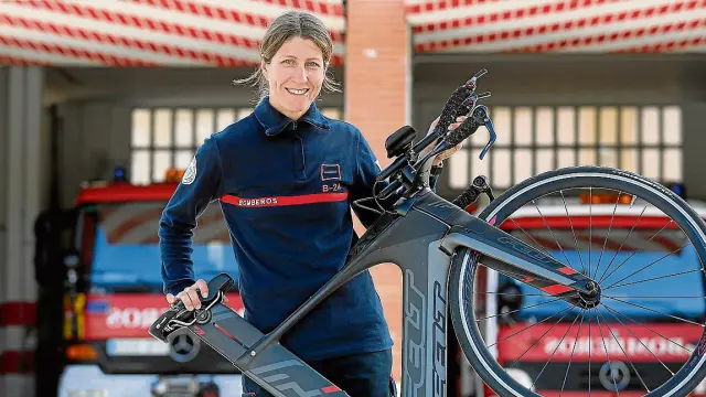Til muestra orgullosa su bici de triatleta frente al parque de bomberos de Huesca, donde trabaja.