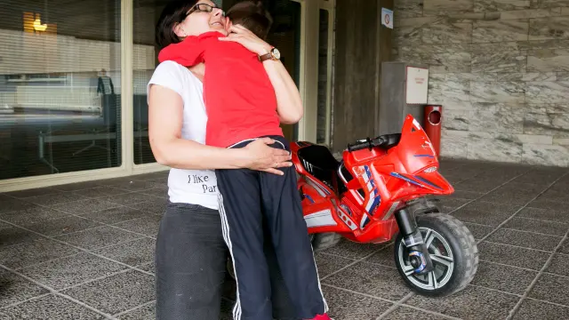 Carmen Baltasar juega con su hijo Sergio a la entrada del hospital donde el niño asiste a sesiones de tratamiento.