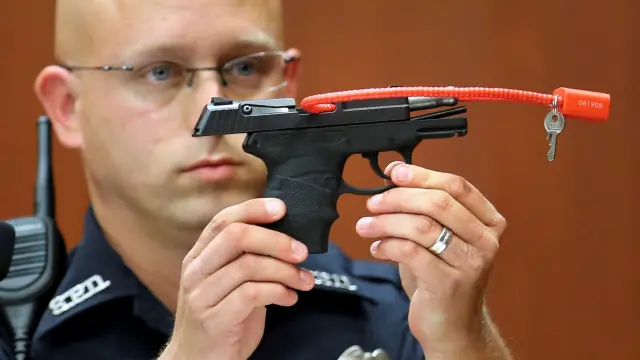 Un agente sostiene el arma con la que fue asesinado el joven durante uno de los juicios.