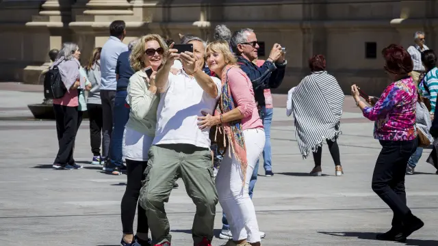 Unos turistas se fotografían en la plaza del Pilar.