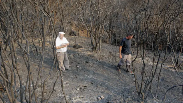Dos vecinos de Porto do Son (La Coruña) contemplan los efectos del incendio forestal que ha arrasado 1.000 hectáreas en su término.