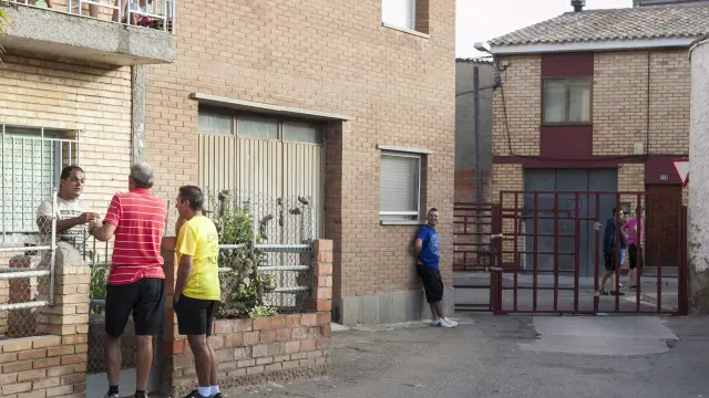 El padre de la niña, a la izquierda, hablando con unos vecinos junto a la valla que abrió el novillo.