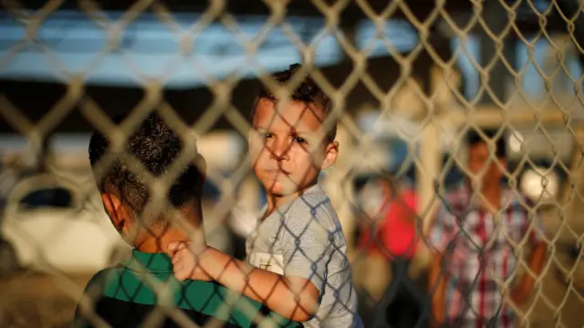 Un niño y un joven esperan a sus familiares en la frontera entre la Franja de Gaza y Egipto, abierta durante dos días por cuestiones humanitarias.