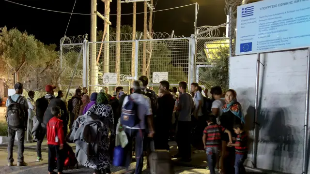 Refugiados y migrantes permanecen delante de la puerta del campo de migrantes de Moria después de declararse un incendio.