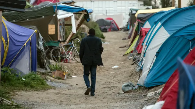 Un migrante camina en por el campamento de Calais, al norte de Francia