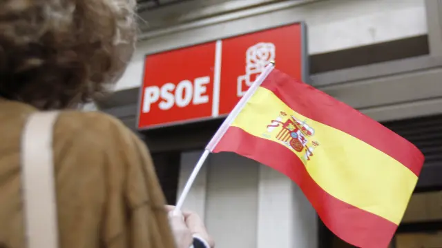 Una mujer hondea la bandera de España frente a la sede del PSOE en Madrid