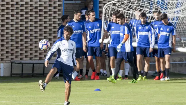 Luis Milla juega con un balón mientras los jugadores trasladan una portería móvil durante el entrenamiento.
