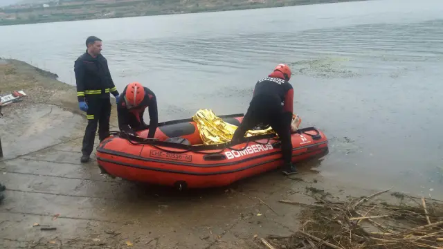 Los bomberos llegan a tierra con el cadáver del pescador ahogado en el embalse de Ribarroja.