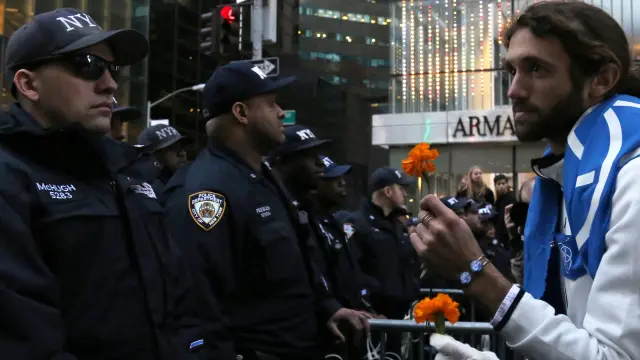 Uno de los manifestantes en protesta por Trump tiende una flor a los policías desplegados en Manhattan.