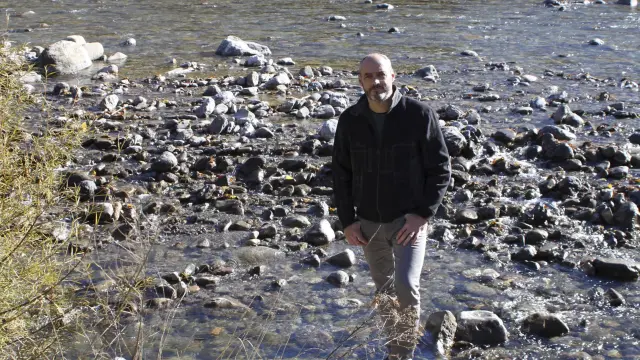 El alcalde de Villanúa, Luis Terrén, en el río Aragón al que vierten las aguas.