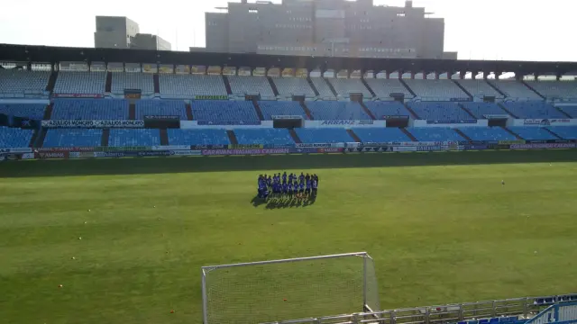 La plantilla del Real Zaragoza, en el habitual corro incial, antes del inicio del entrenamiento de este sábado en La Romareda.