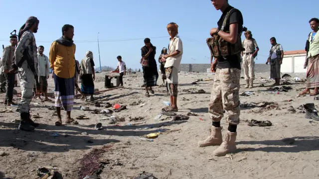 Un grupo de yemenís se reúnen en torno al cuartel atacado, tras el atentado