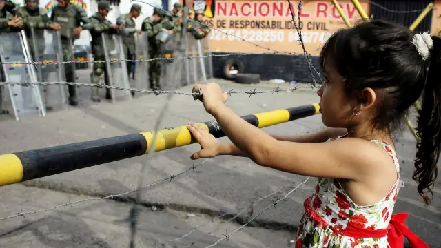 Una niña frente a una verja fronteriza entre Colombia y Venezuela