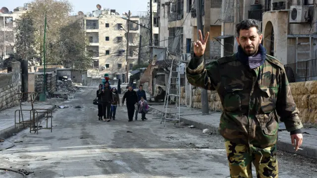 Un soldado sirio muestra el símbolo de la victoria en una devastada Alepo