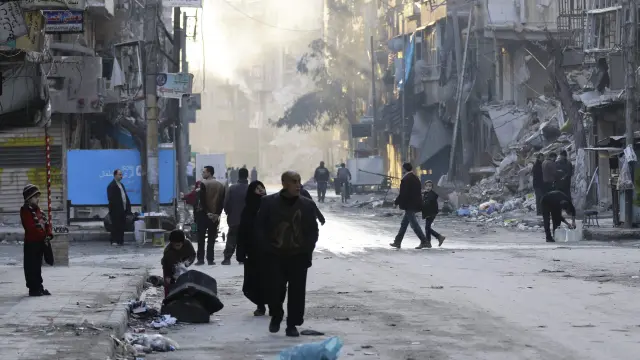 Varios civiles caminan  por las calles destruidas de Alepo.