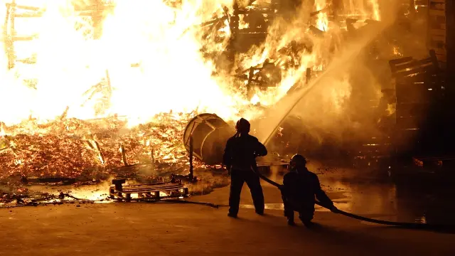 El fuego sigue devorando varios palets apilados junto al almacén. Digital Fraga TV.