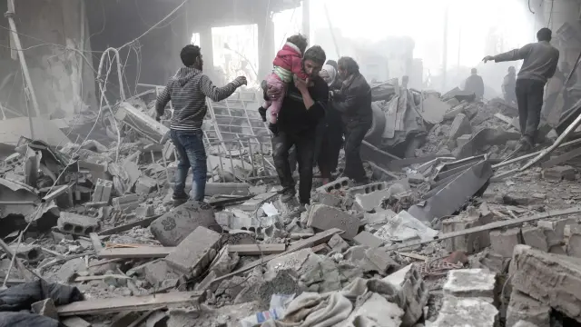 Los voluntarios de la defensa civil de Siria, también conocidos como cascos blancos, dan instrucciones a los bomberos mientras intentan extinguir el fuego tras haber denunciado un ataque aéreo en la ciudad siria de Douma