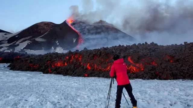 Imagen de un turista en la ladera del Etna con una colada ardiente