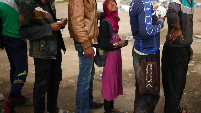 Habitantes de Mosul que han huido de la ciudad a causa del Estado Islámico esperan recibir comida a las afueras
