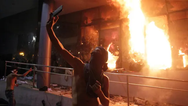 Un manifestante se hace un selfi frente al Congreso en llamas