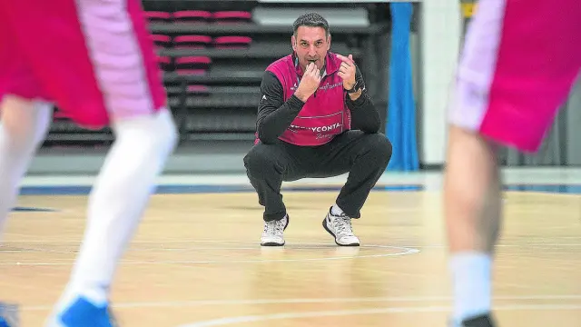 El entrenador Luis Guil, agachado y con el silbato en la boca, observa los movimientos de sus jugadores durante un entrenamiento.