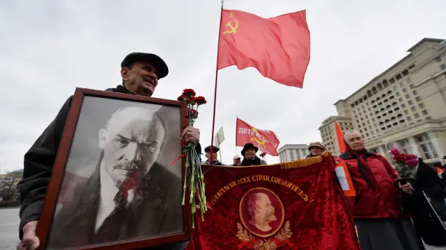 Un grupo de comunistas rusos portan un retrato de Lenin, banderas y flores en la Plaza Roja de Moscú.