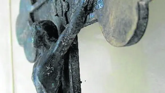 El crucifijo lobulado que sale a la venta está fabricado en bronce y presenta indicios de haber sido expuesto al fuego, lo que destruyó adornos y elementos de la madera. Mide 24 por 13 centímetros.