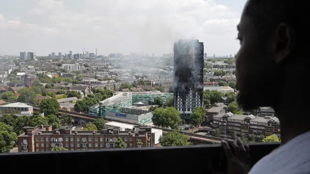 Un hombre observa el edificio devastado por las llamas.
