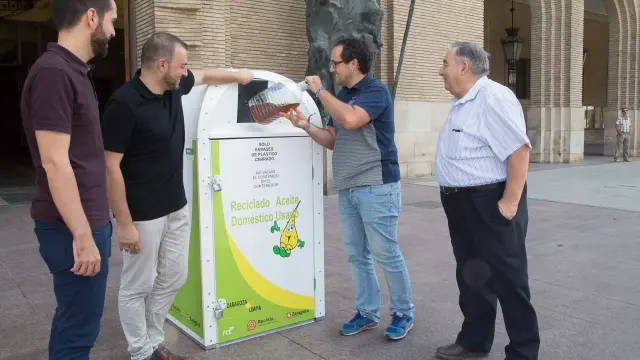 El consejero de Servicios Públicos, Alberto Cubero, recicla aceite en un contenedor junto al presidente de Adislaf, José María López (a la derecha).