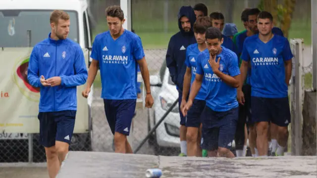 Los jugadores del Real Zaragoza llegan al campo de Villaboya de Boltaña en medio de un intenso aguacero de tormenta en la mañana de este viernes.