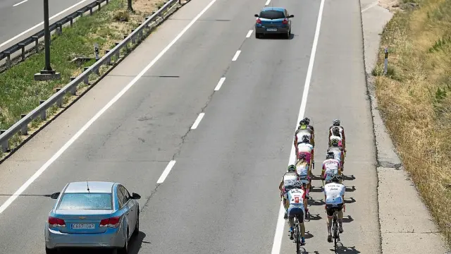 Un grupo de ciclistas circula por la carretera de Valencia mientras un vehículo adelanta correctamente.