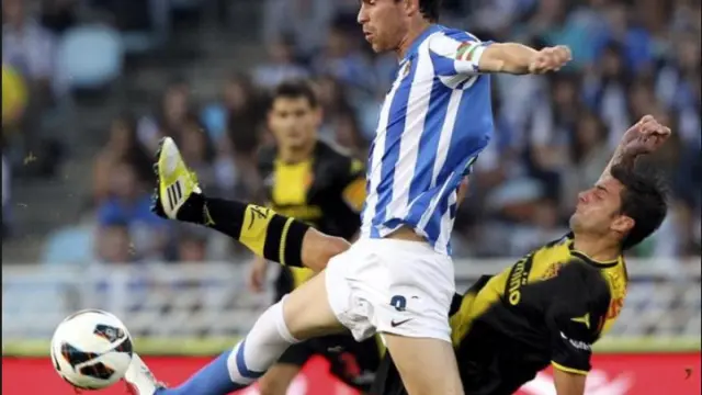 Mikel González, con el brazalete de capitán de la Real Sociedad, corta un avance de Hélder Postiga, ariete del Real Zaragoza, en el último partido entre ambos equipos en Primera División hace cuatro años en Anoeta (al fondo, Paredes).