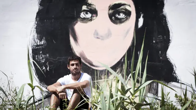 Luis Costa, delante del mural que ha pintado la artista castellonense Paula Bonet este verano en Grañén.