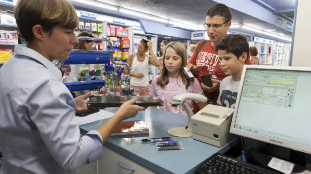 Una familia compra material escolar en la Librería General de Zaragoza.