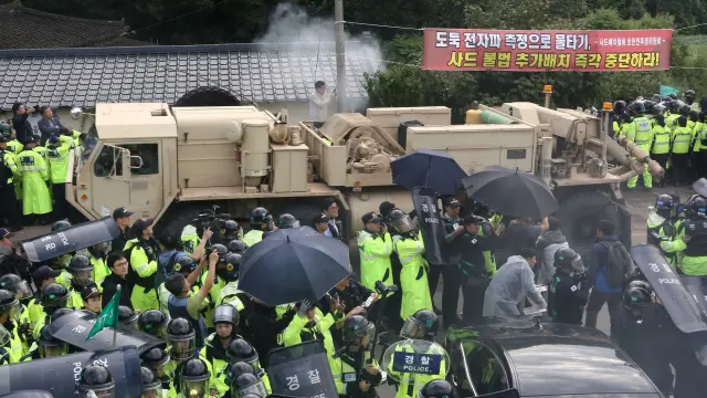 Residentes y miembros de grupos cívicos forcejean con los antidisturbios para intentar bloquear un vehículo militar del ejército de Estados Unidos.
