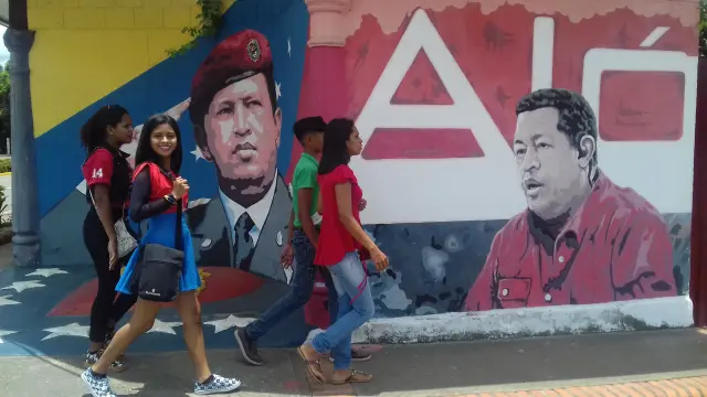 Jóvenes pasan ante un cartel de Chávez en la localidad venezolana de Sabaneta.