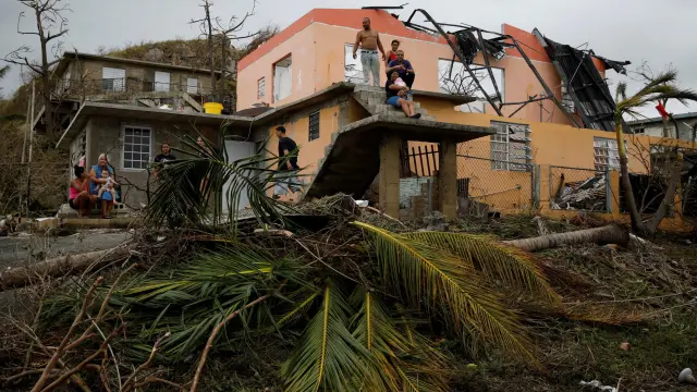 Los habitantes de una de las zonas afectadas por el paso del huracán María, en Puerto Rico, permanecen en el exterior de sus casas, que han sido dañadas por este.
