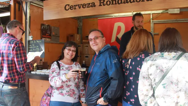 Dos vecinos de la capital aragonesa brindan con cerveza Rondadora en la Muestra de Artesanía Alimentaria de la plaza de los Sitios.