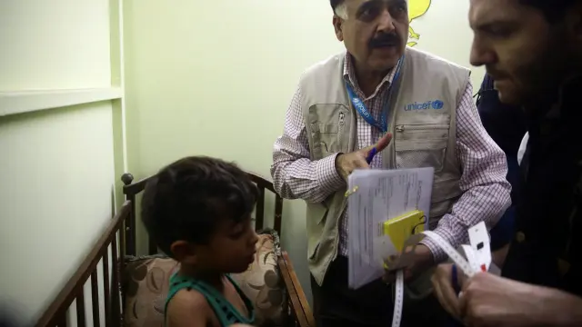 Un sanitario de Unicef examina a un niño en un suburbio de Damasco.