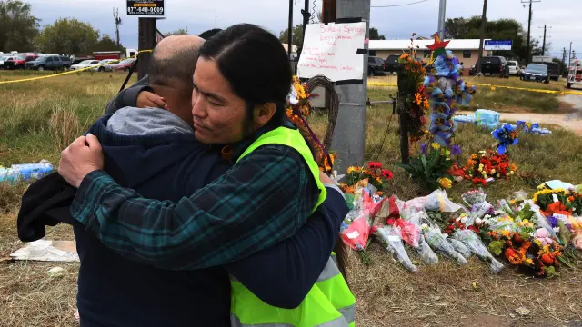 Dos hombres se abrazan ante el memorial de las víctimas de Texas.