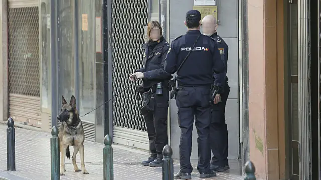 Tres efectivos de la Policía Nacional junto al perro de los Tedax, en la puerta del consulado de Francia en Zaragoza.