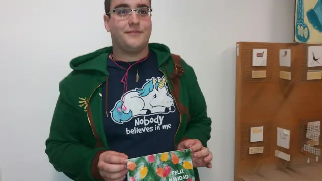 El ganador del concurso posa con la tarjeta navideña que ha diseñado.