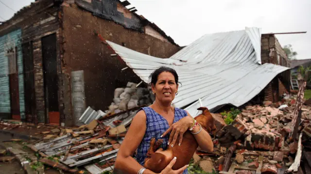 Una mujer posa junto a su casa destruida por el huracán Irma en Cuba