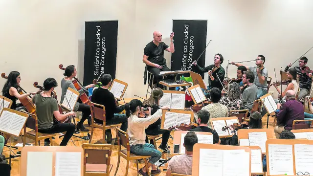 El director Juan Luis Martínez y los músicos de la Sinfónica Ciudad de Zaragoza, durante el ensayo de ayer.