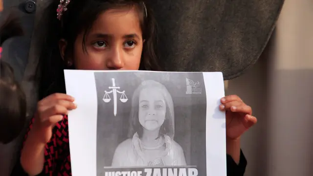 Una niña sujeta la foto de Zainab Ansari, la niña asesinada