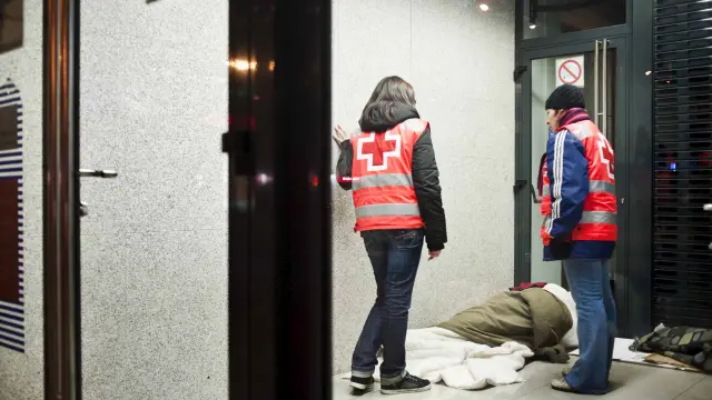 Dos voluntarios de Cruz Roja atienden a un sin techo en Zaragoza