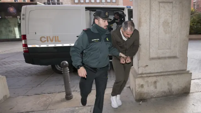 Uno de los detenidos, esposado, es conducido por la Guardia Civil desde el furgón de seguridad al Juzgado