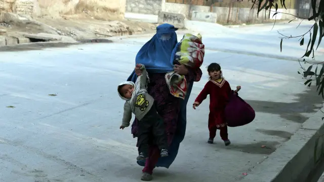 Una mujer huye con tres niños de la zona atacada.
