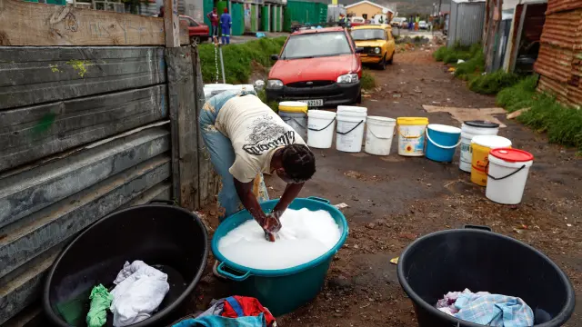 Una mujer lava su ropa con agua recolectada de un grifo comunitario